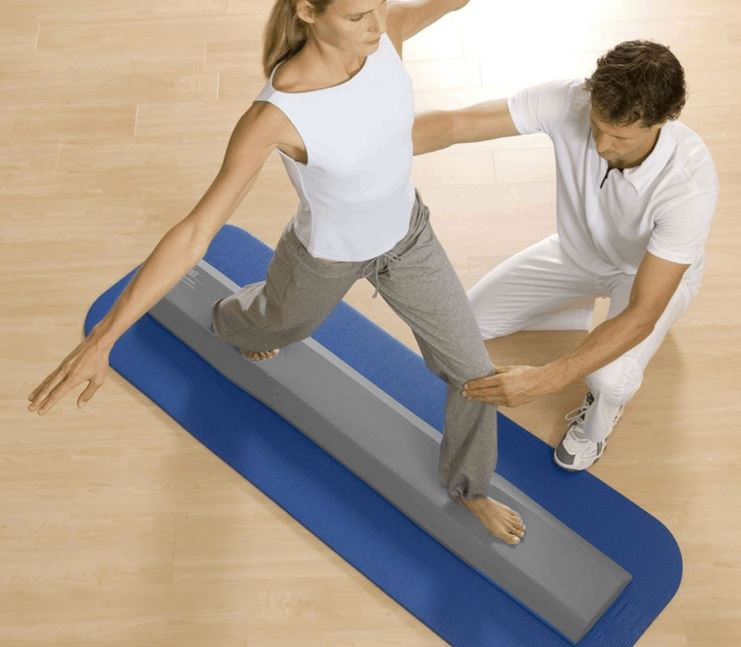 jeune femme utilisant un balance beam airex pour un exercice de kinésithérapie 