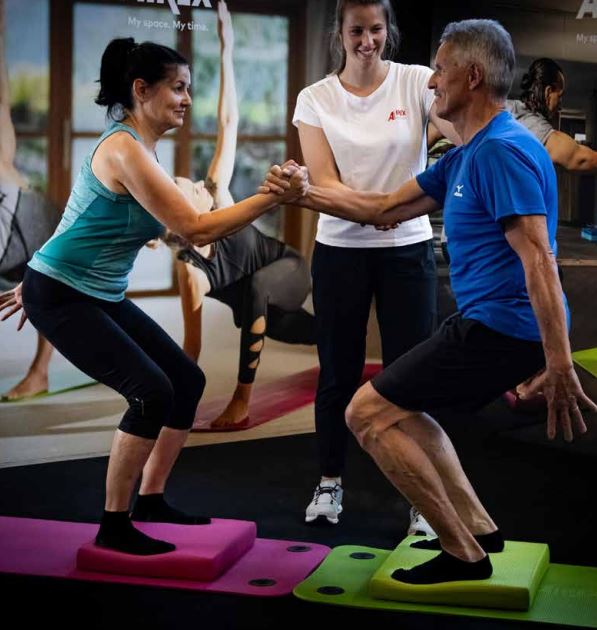 deux séniors qui urilisent le balance pas airex pour un exercice de kinésithérapie