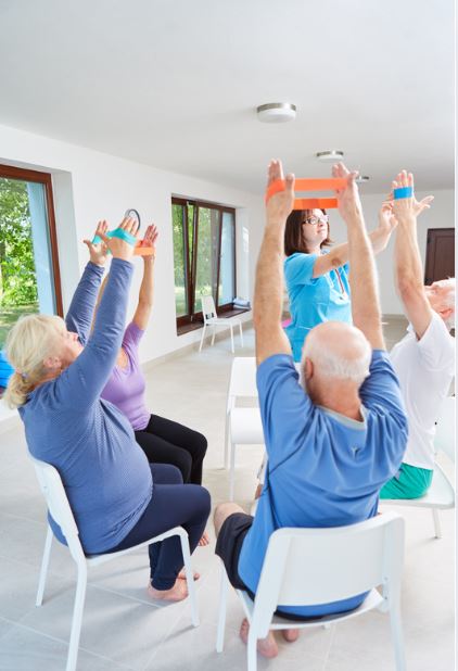 Exercice de rééducation pour séniors avec bande élastique réalisé avec un kinésithérapeute au cabinet