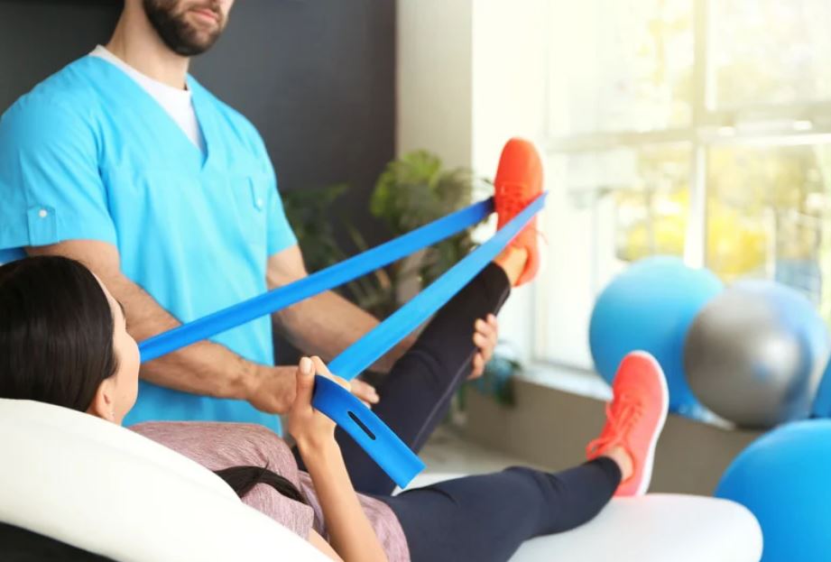 Exercice de rééducation avec bande élastique réalisé avec un kinésithérapeute au cabinet