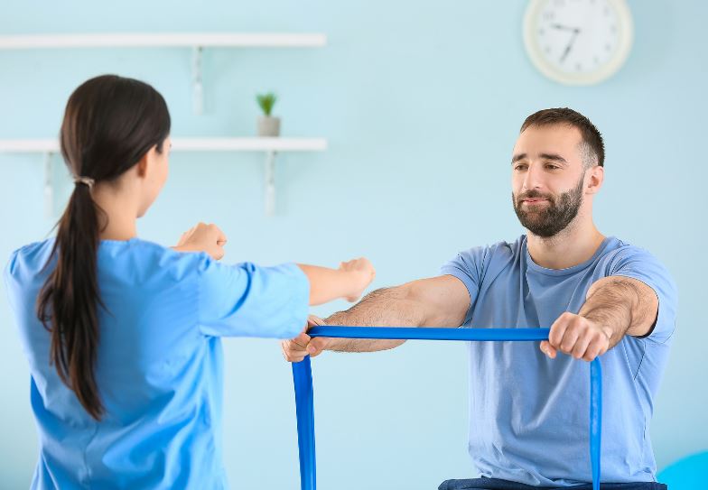 Exercice de rééducation avec bande élastique réalisé avec un kinésithérapeute au cabinet