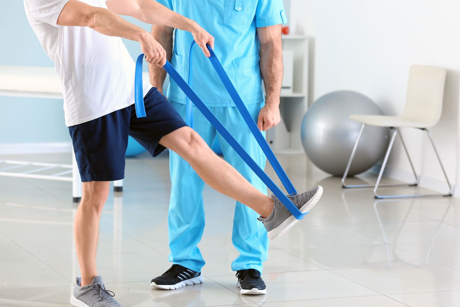 Exercice de rééducation de la hanche avec bande élastique réalisé avec un kinésithérapeute au cabinet