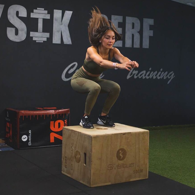 Une femme qui saute sur une plyobox lors d'une séance de crosstraining