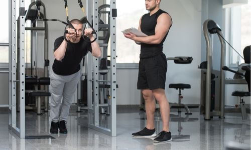 un homme travaillant avec des sangles TRX dans une cage de crosstraining