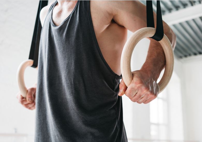 un homme se souleve avec des anneaux de gymnastique pendant une séance de crosstraining
