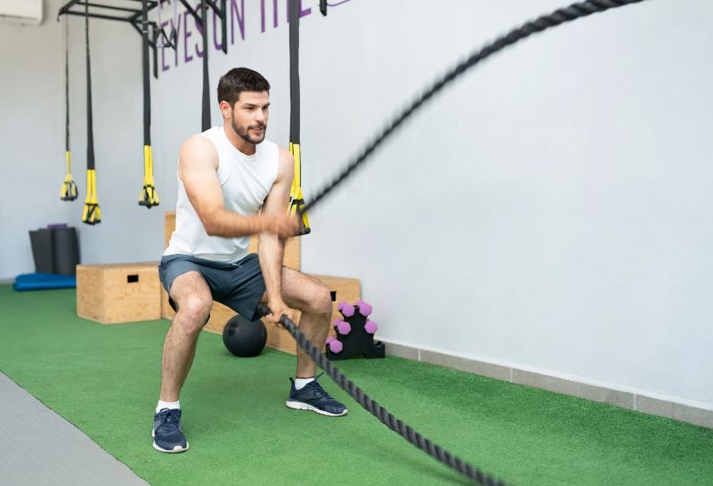 un homme qui utilise une corde d'oscillation lors d'une séance de crosstraining