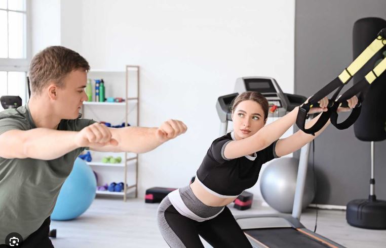 un kiné qui explique à sa patiente comment uriliser les sangles TRX en crosstraining