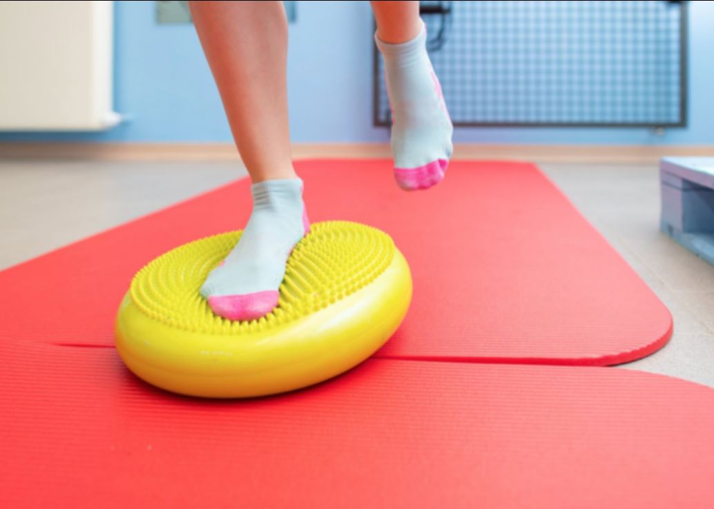 Travail de stabilité sur Bosu pour rééducation d’une entorse de cheville bandée en cabinet de kinésithérapie