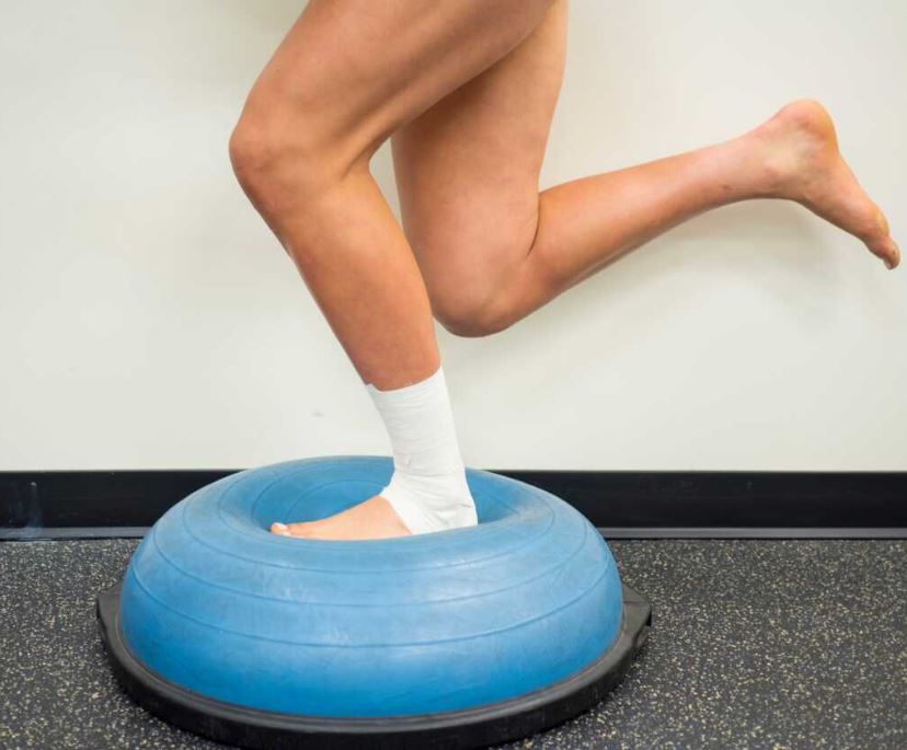 Travail de stabilité sur Bosu pour rééducation d’une entorse de cheville bandée en cabinet de kinésithérapie