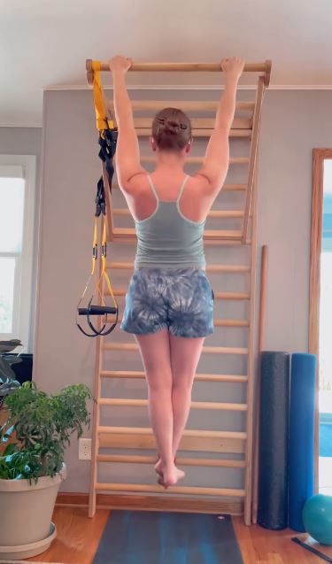 Exercice de traction en supension sur un espalier en cabinet de kinésithérapie