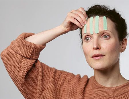 une femme avec du kinésio ligth touch sur le visage en application face taping