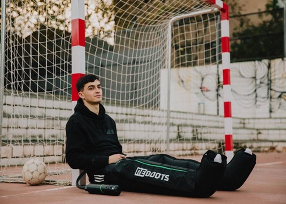 Footballeur assis portant des bottes Reboots Go Lite