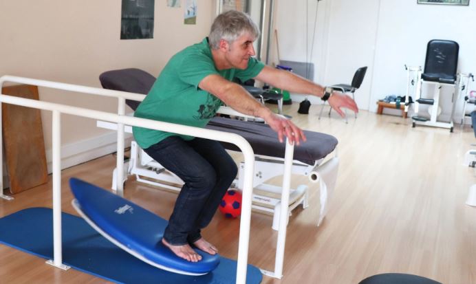 Une personnes avec troubles neurologique entrain de se réeduquer avec la Toyboard et des barres parallèles