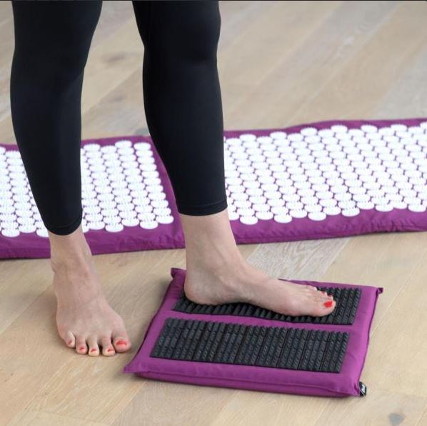 Pieds sur un tapis d'acupression plantaire, utilisée pour la détente musculaire en kinésithérapie