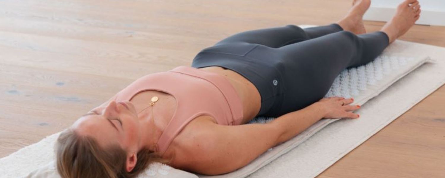 Patiente allongée sur un tapis avec un tapis d’acupression, utilisée pour la détente musculaire en kinésithérapie