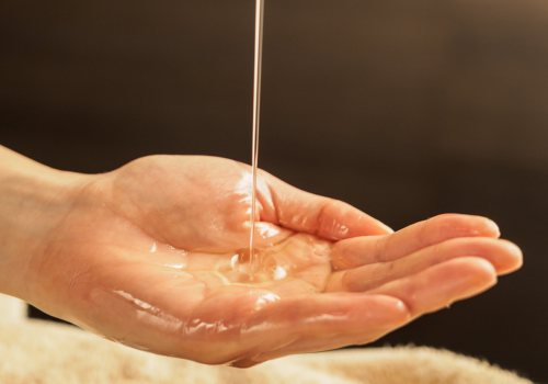 huile de massage qui coule dans le creux d'une main pour la kinésithérapie