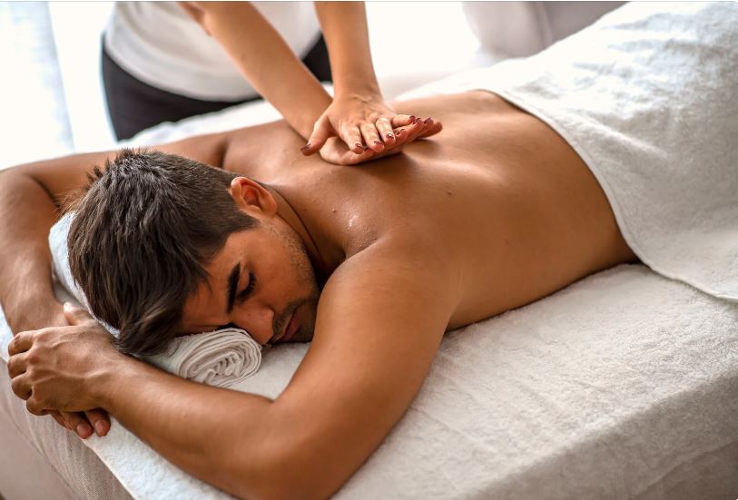 Homme se fesant masser le dos par un kinésithérapeute 