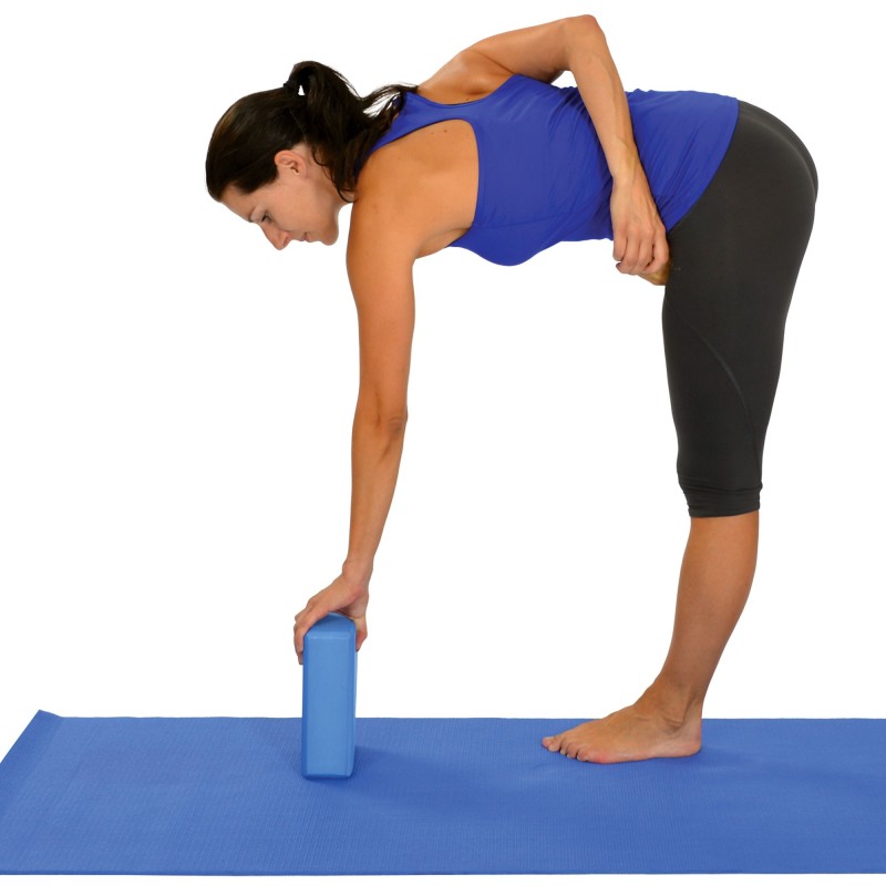 femme faisant l'étirement des ischio-jambiers avec bloc de yoga, en position debout, tronc incliné vers l’avant