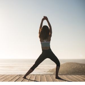 Femme pratiquant le Pilates en plein air face à la mer pour le bien-être du corps