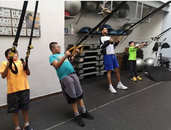 Groupe d'enfants réalisant des exercices à l'aide des sangles de suspsension TRX