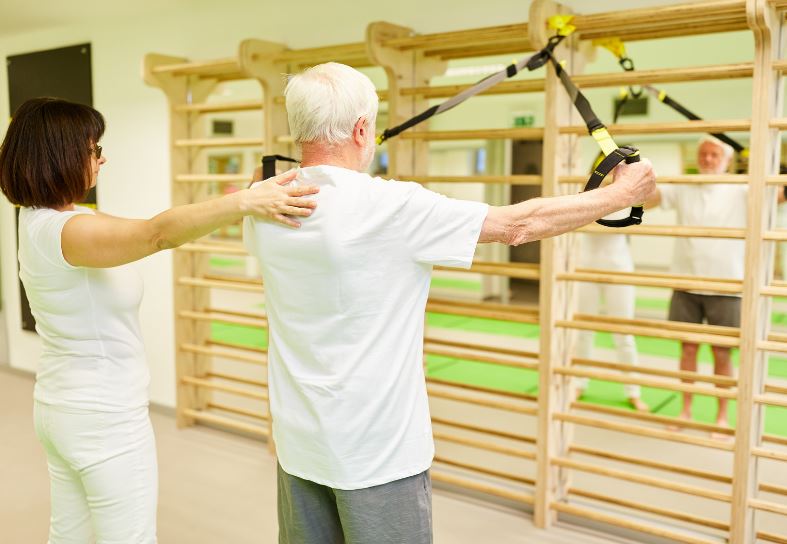 Personnes agées utilisant les sangles TRX pour la réeducation à l'aide de son kinésithérapeute