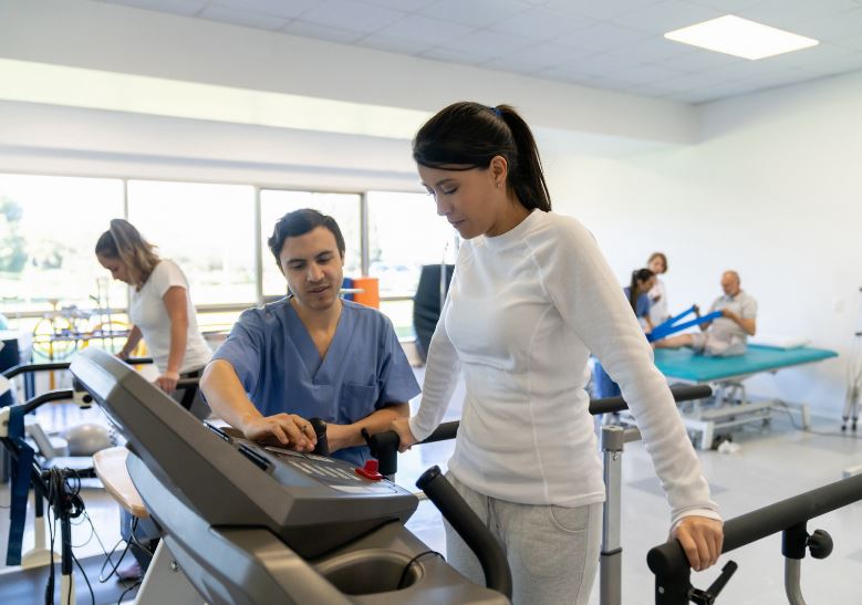 kiné et patiente en exercice de rééducation sur un tapis de marche tunturi platinum