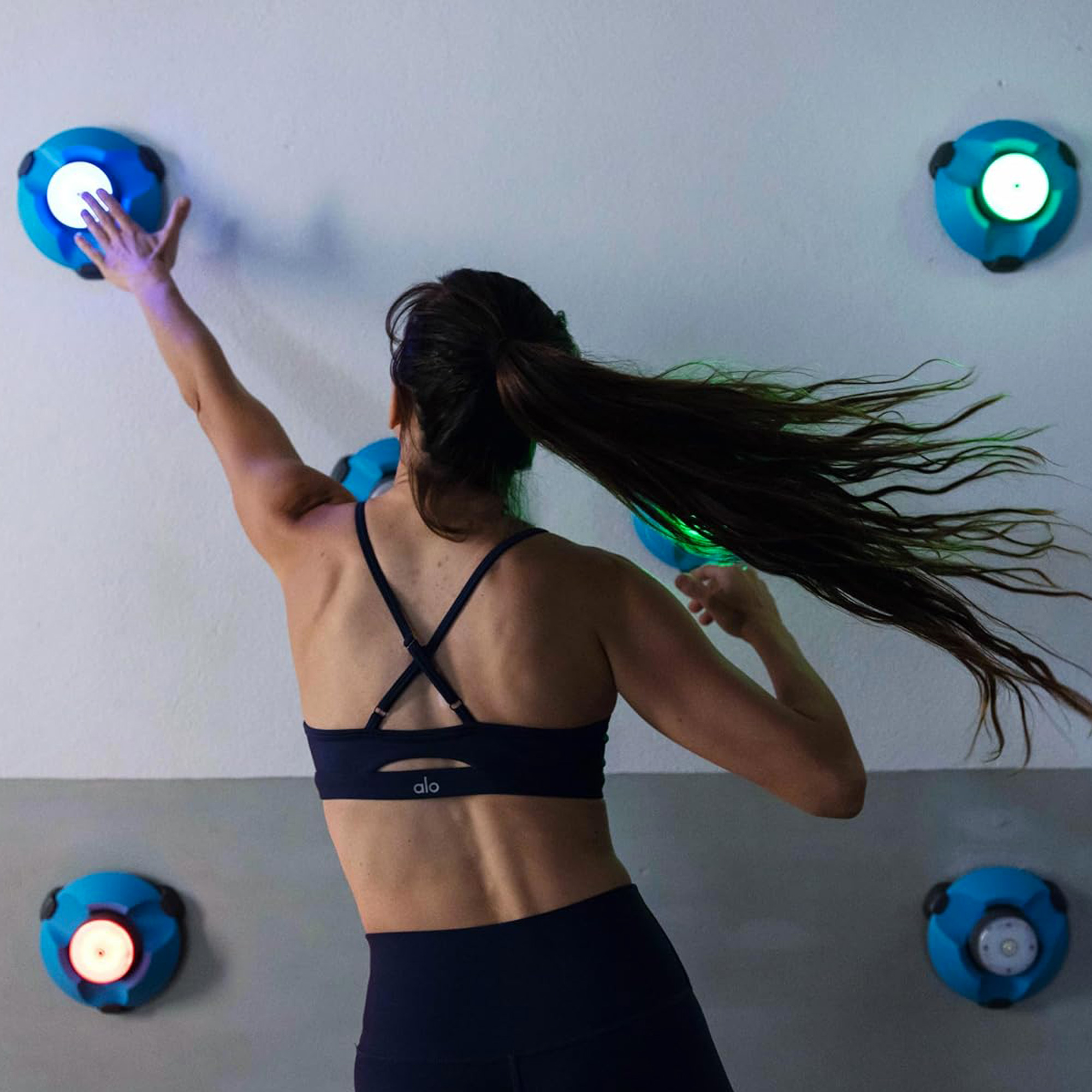 Femme qui fait un exercices avec les blazepods au mur en kinésithérapie